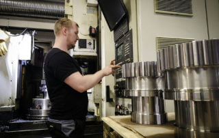 Man working on a CNC machine for making gears.